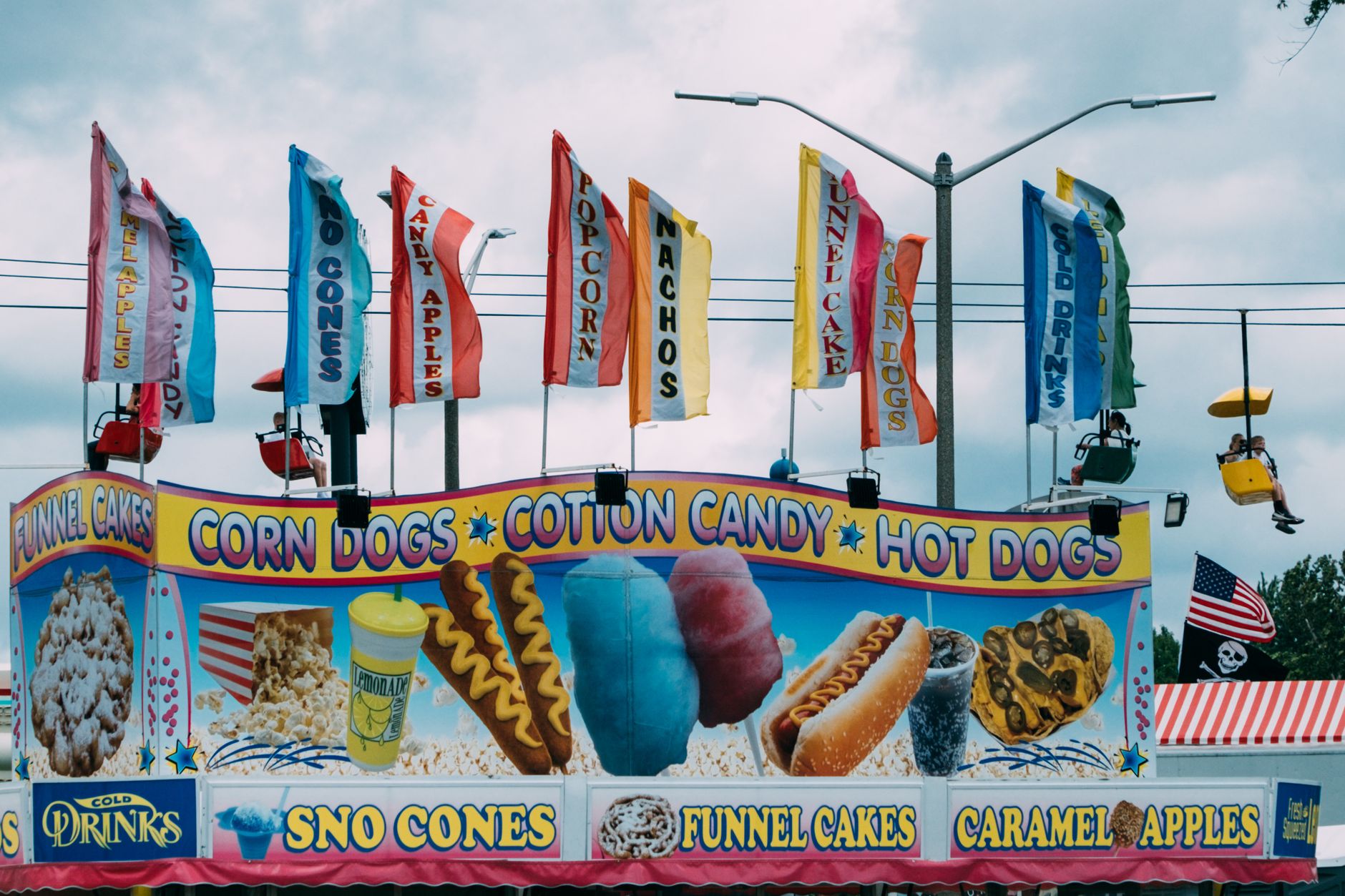 Brightly colored carnival stand selling various snacks such as corn dogs and cotton candy.